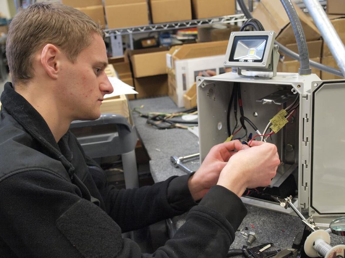 A student wires a solar-powered lamppost that will be used in Africa.